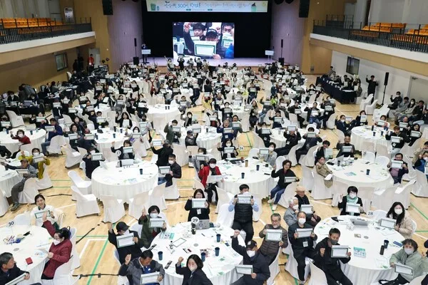 안성시민 원탁토론 현장에서 참가자들이 원탁마다 무선투표 단말을 들어 보이는 전경