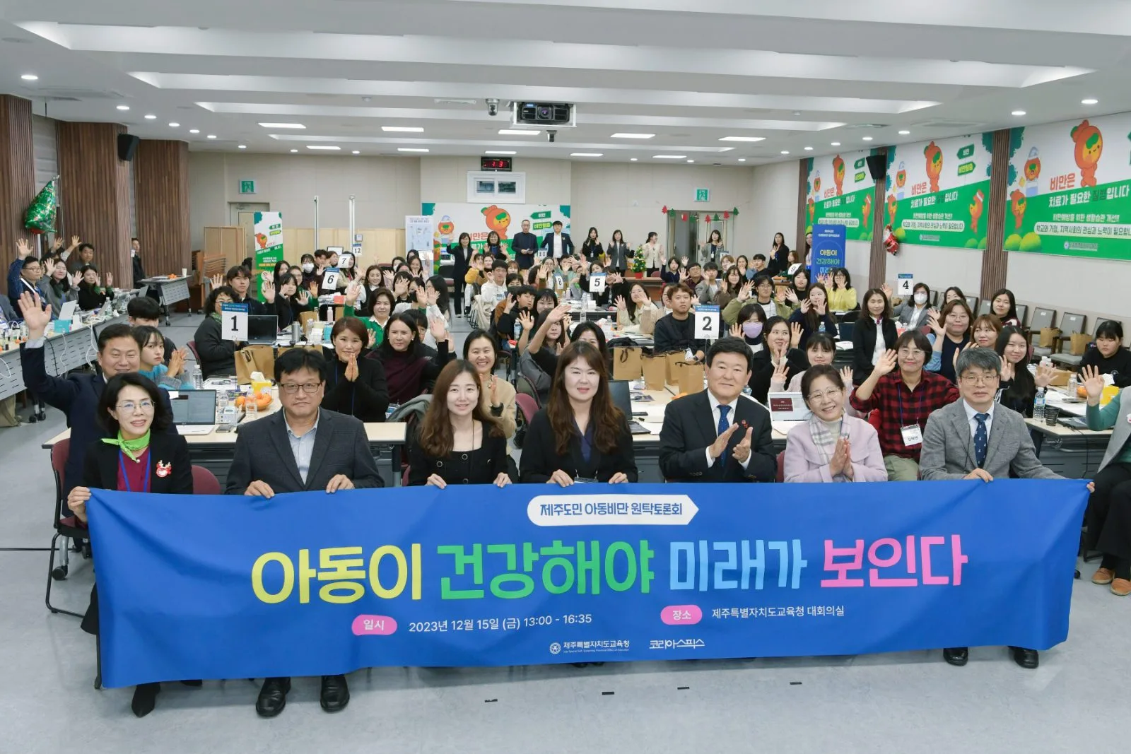 제주도민 아동비만 원탁토론회 참가자들이 ‘아동이 건강해야 미래가 보인다’ 현수막 뒤로 모여 있는 모습