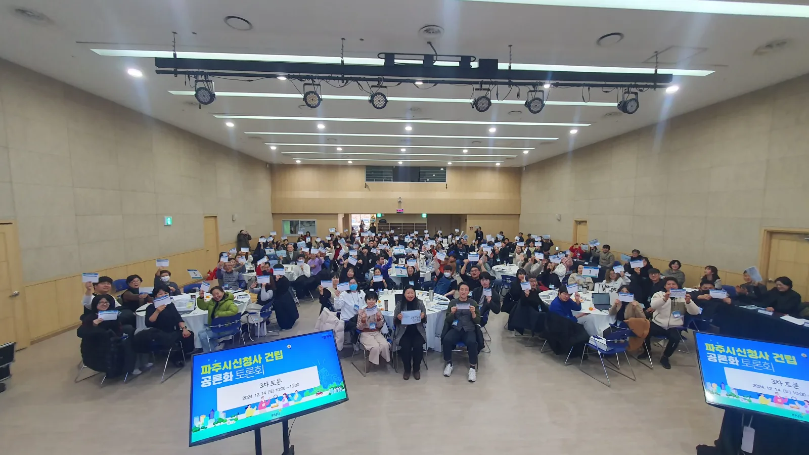 파주시 신청사 건립 공론화 토론회 3차 토론에서 원탁에 앉은 참여단이 배부받은 자료를 들어 보이는 전경