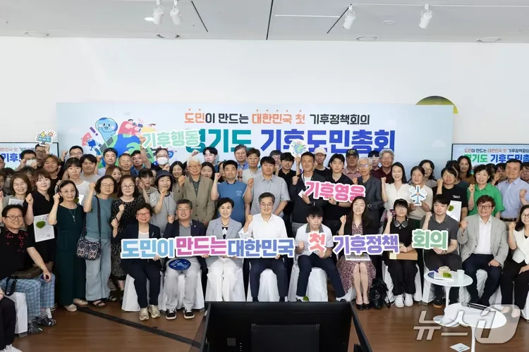 경기도 기후도민총회 참가자들이 무대 앞에 모여 기후정책회의 손팻말을 들고 있는 모습