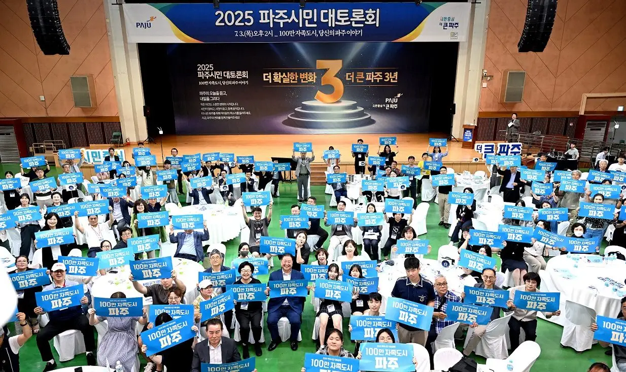 2025 파주시민 대토론회에서 원탁에 앉은 참가자들이 ‘100만 자족도시 파주’ 손팻말을 들어 올린 전경